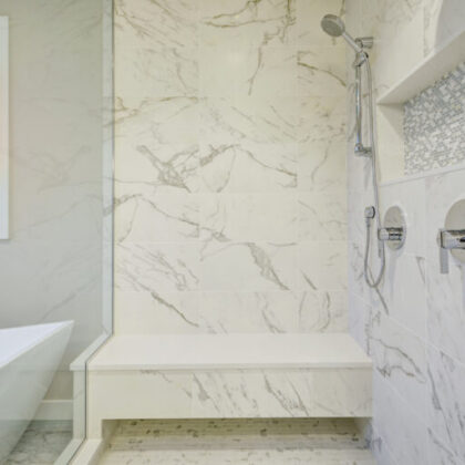 Sleek bathroom features freestanding bathtub and glass shower accented with rain shower head and gray and white marble surround. Northwest, USA