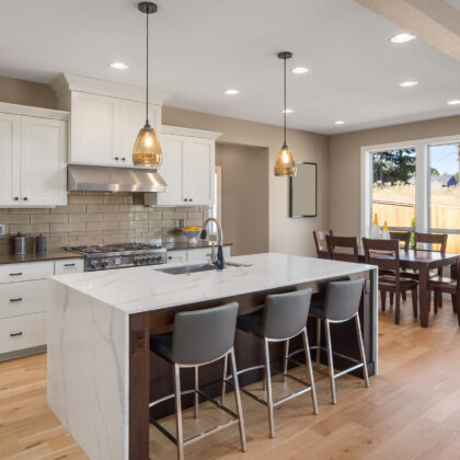 Kitchen in new home with stainless steel appliances, island, and pendant lights. Shows dining area.