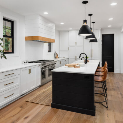 Beautiful white kitchen with dark accents in new modern farmhouse style luxury home